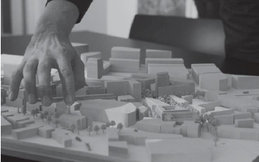 close up of person's hand above an architectural model of a town