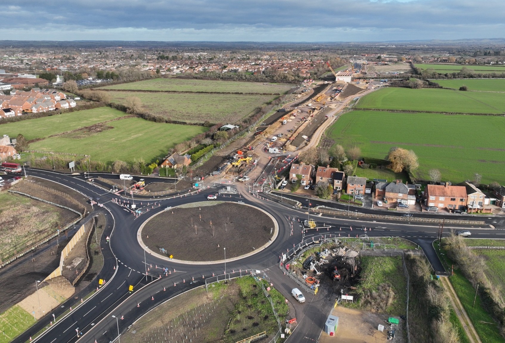 Aerial view of a road improvement scheme showing a newly constructed roundabout, roadworks, surrounding fields and nearby residential development.