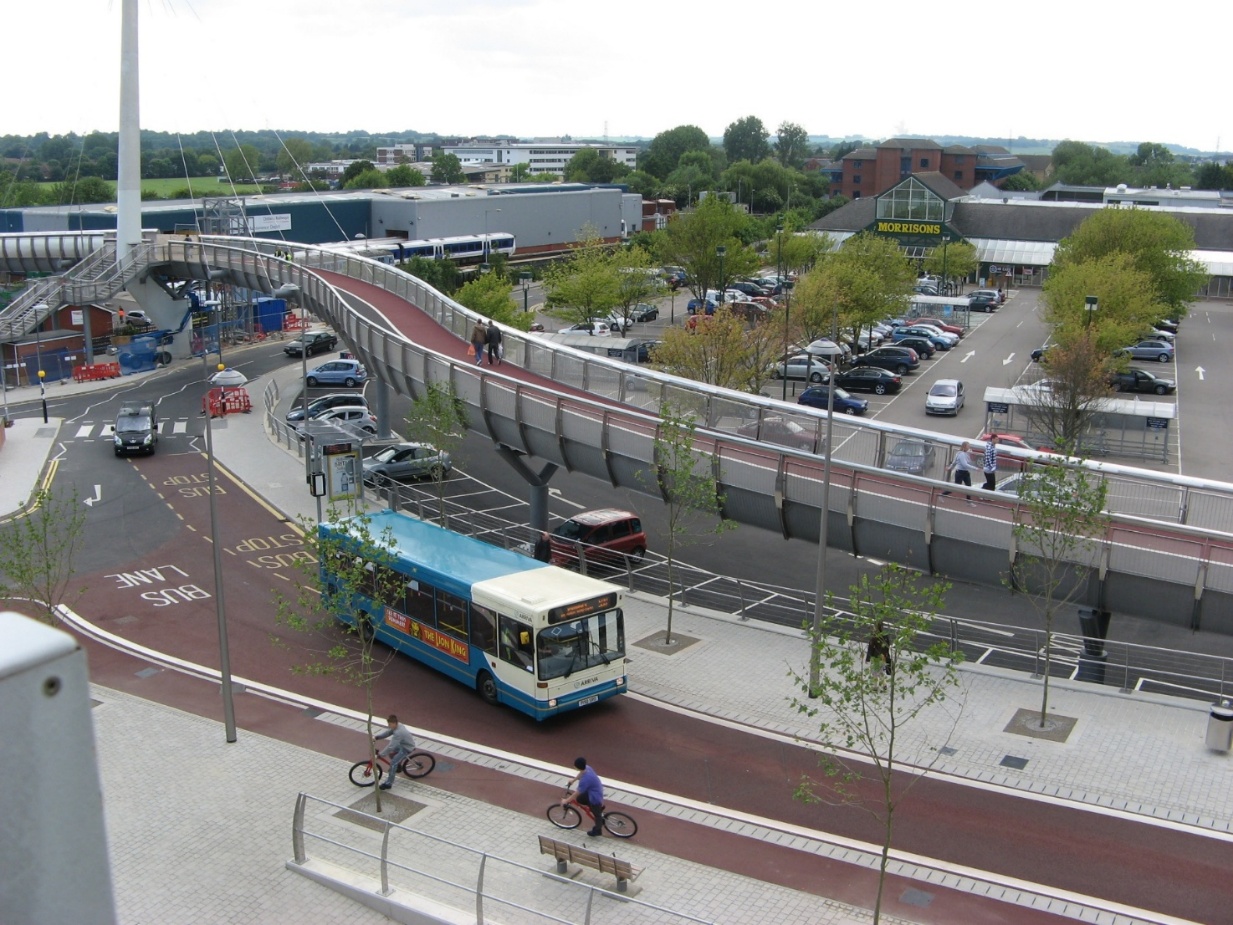 Bus travelling along a dedicated bus lane, with cyclists using a cycle lane and pedestrians on an elevated footbridge